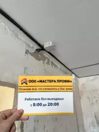 электрик соединяет провода в распределительной коробке на бетонной стене